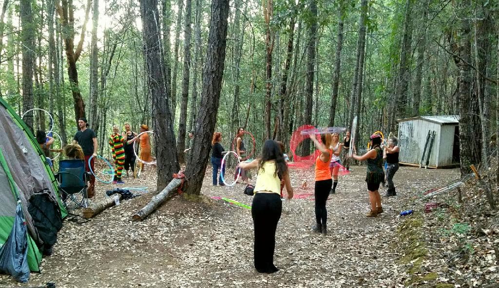Flow artists gathering with hoops along a wooded camp path