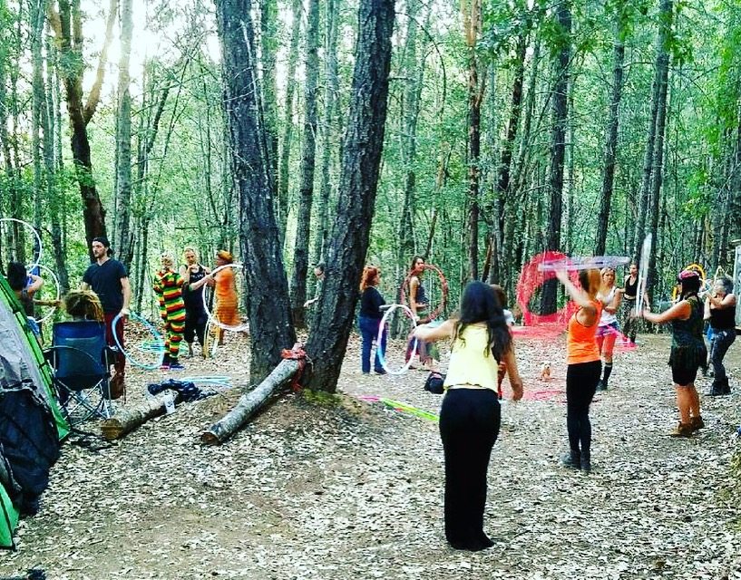 Flow artists practicing with hoops among tall trees